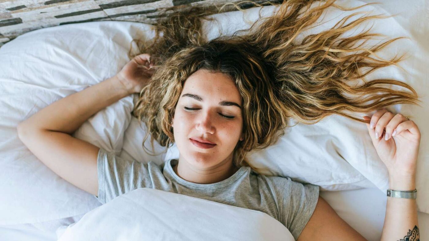 Person sleeping on side with face pressed against pillow showing compression lines and silk pillowcase alternative